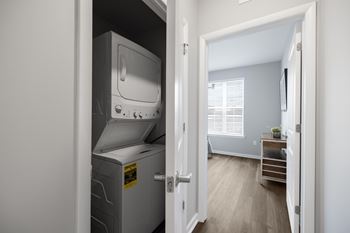 A small room with a white fridge and a door open to a hallway.